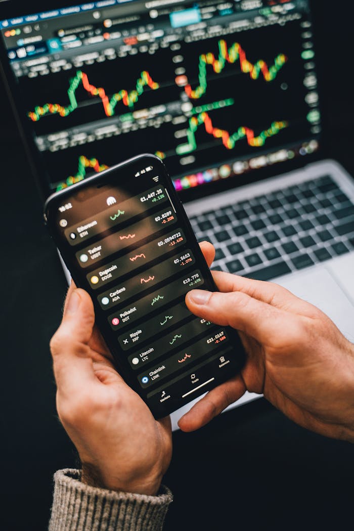 cta-bg Hands holding smartphone with stock app, laptop displaying charts. Perfect for financial and technology themes.