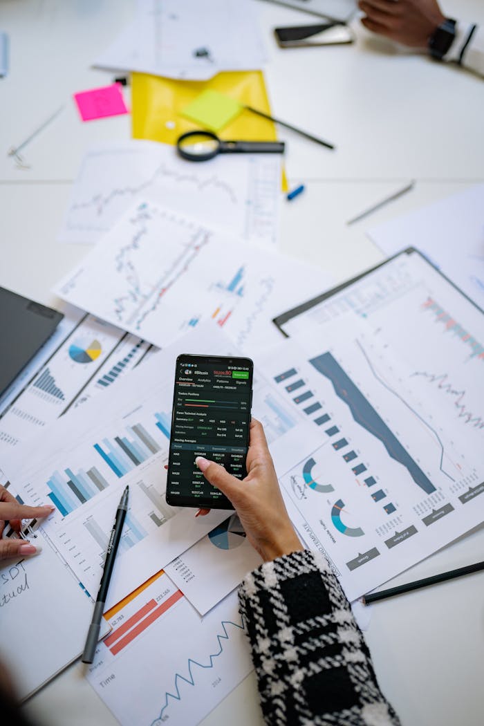 home-hero-bg Person analyzes financial charts using a smartphone in an office setting.
